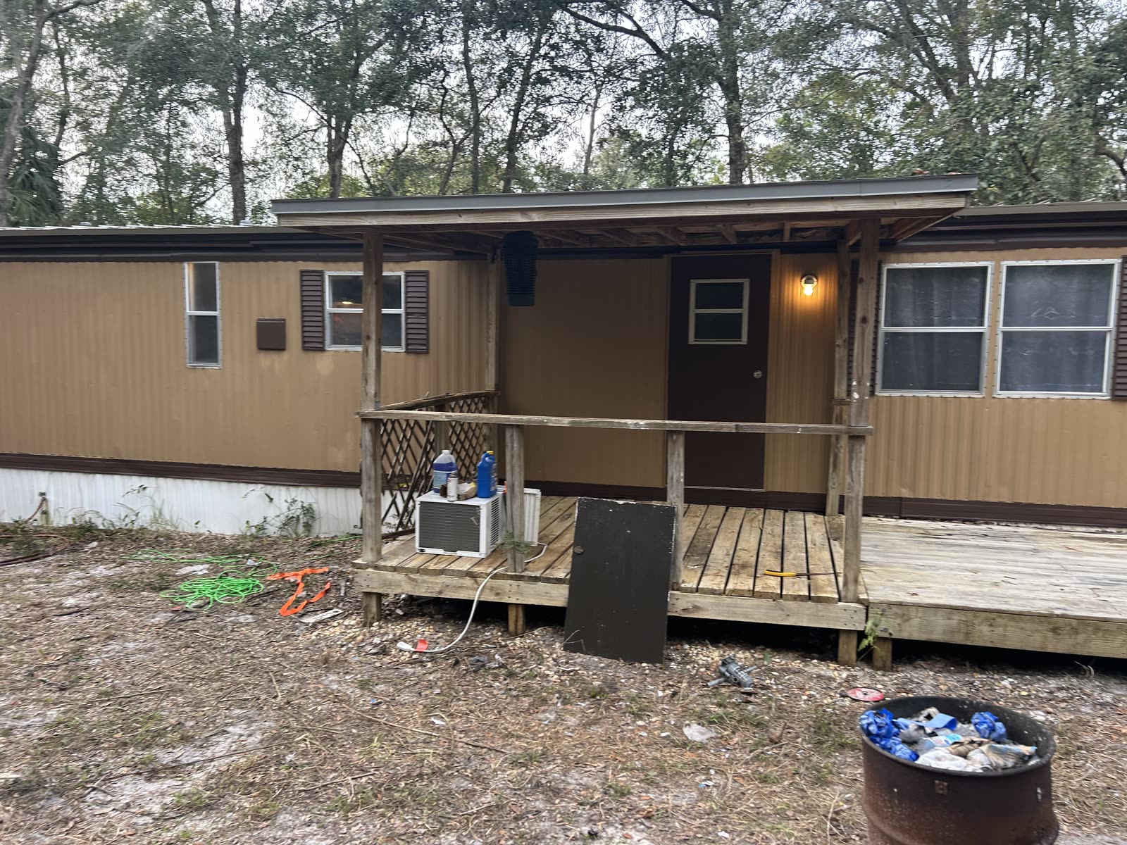 The same mobile home repainted tan with brown trim and a fresh wooden deck