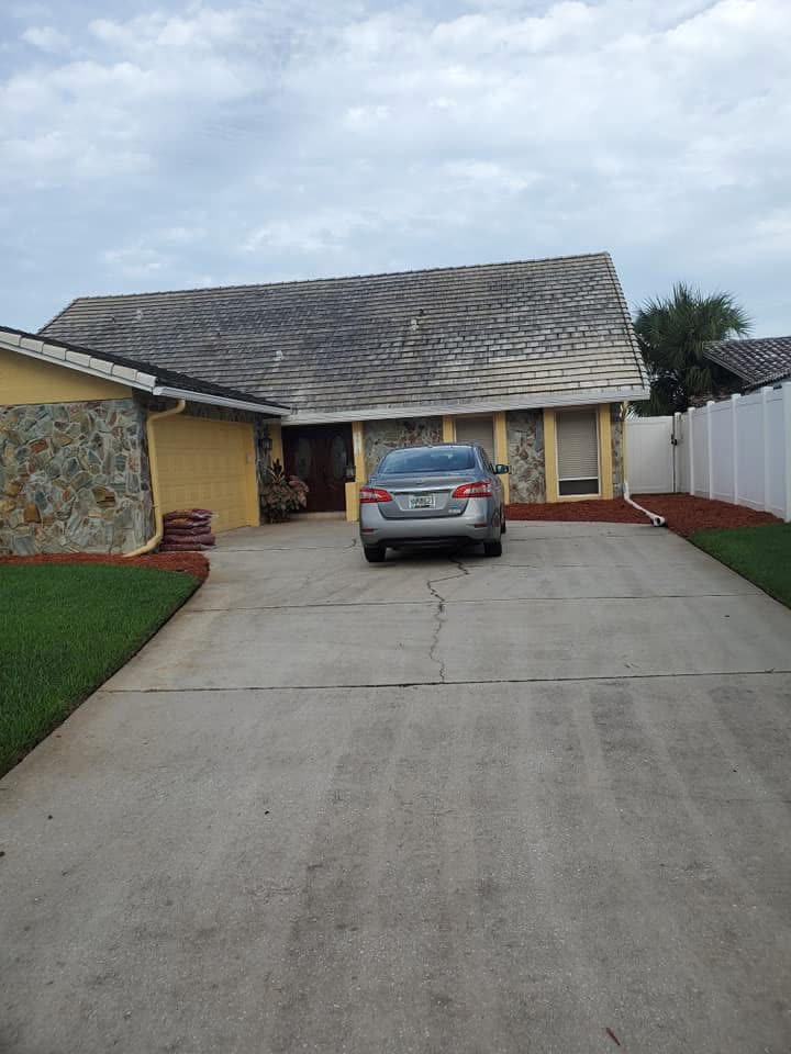 Before: Home with a dark, stained tile roof and a dirty concrete driveway